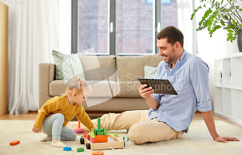 Image of father with tablet pc and baby daughter at home