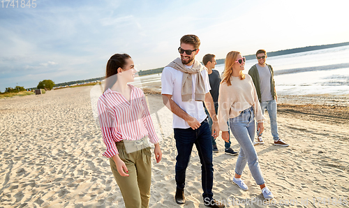 Image of happy friends walking along summer beach