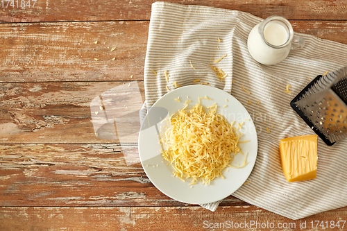 Image of close up of grated cheese and jug of milk on table