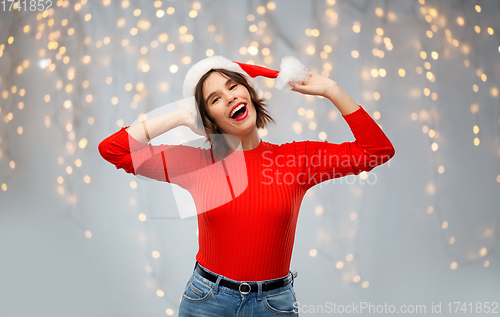 Image of happy young woman in santa hat on christmas