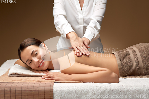 Image of woman lying and having back massage at spa