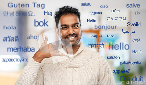 Image of indian man in sweater making phone call gesture