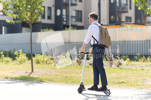 Image of businessman with backpack riding electric scooter