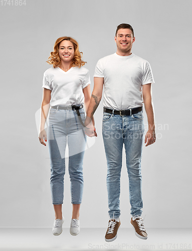 Image of happy couple in white t-shirts jumping or hanging