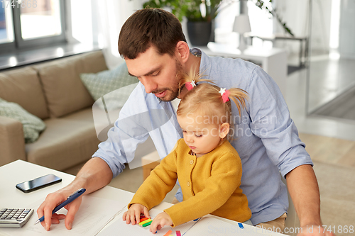 Image of working father with baby daughter at home office