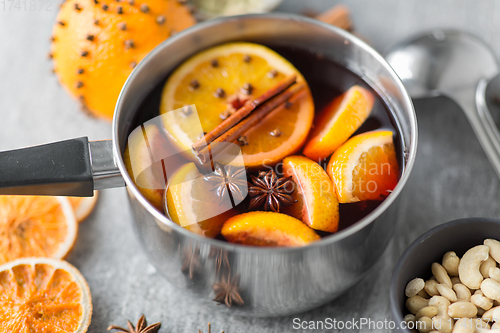 Image of pot with hot mulled wine, orange slices and spices