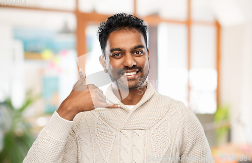 Image of indian man in sweater making phone call gesture