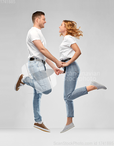 Image of happy couple in white t-shirts jumping