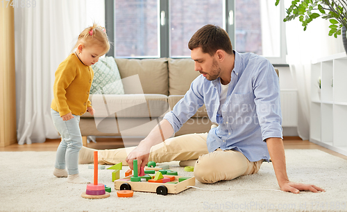 Image of father playing with little baby daughter at home