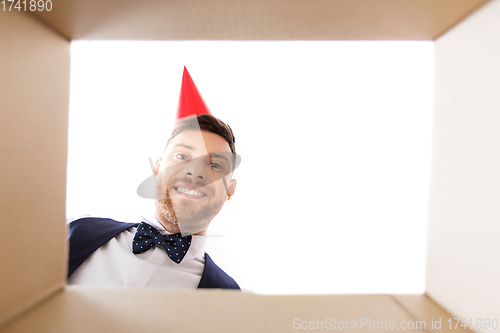 Image of happy young man looking into open birthday gift