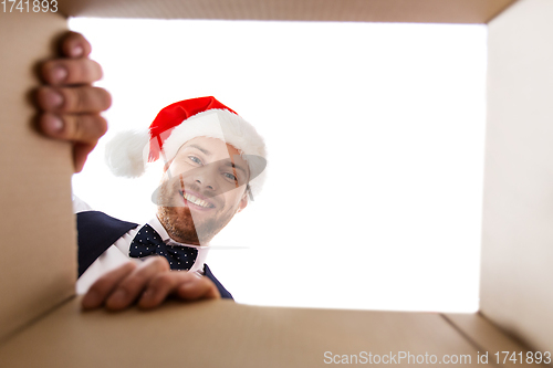 Image of happy young man looking into open christmas gift