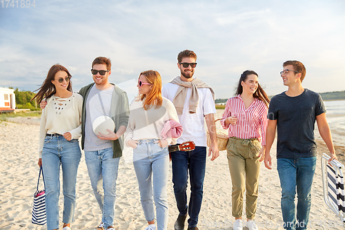 Image of happy friends walking along summer beach