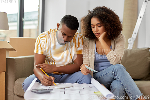 Image of sad couple with blueprint counting money at home