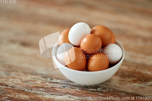 Image of close up of eggs in ceramic bowl on wooden table