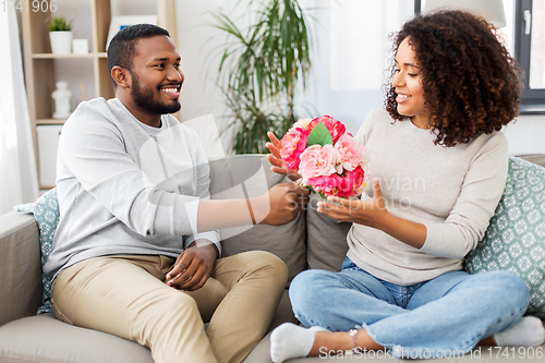 Image of happy couple with bunch of flowers at home