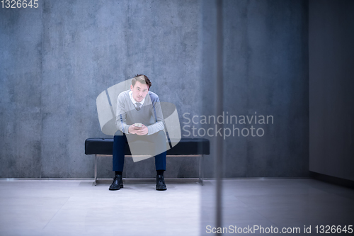 Image of businessman using smart phone while sitting on the bench