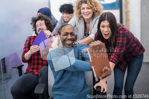 Image of multiethnics business team racing on office chairs