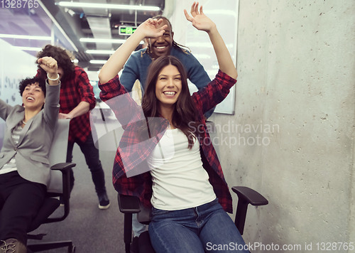 Image of multiethnics business team racing on office chairs