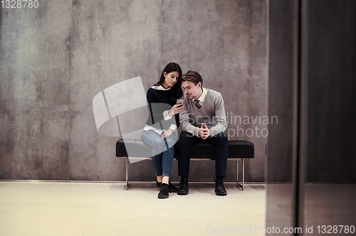 Image of business couple using mobile phone while sitting on the bench