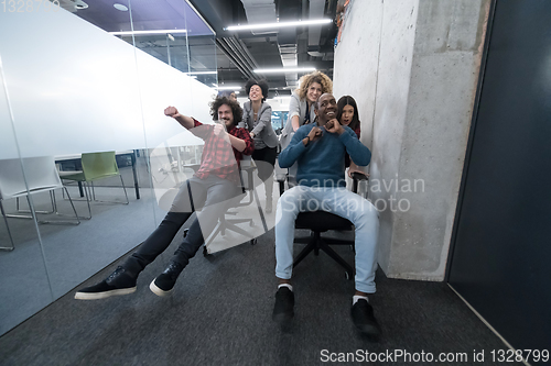 Image of multiethnics business team racing on office chairs