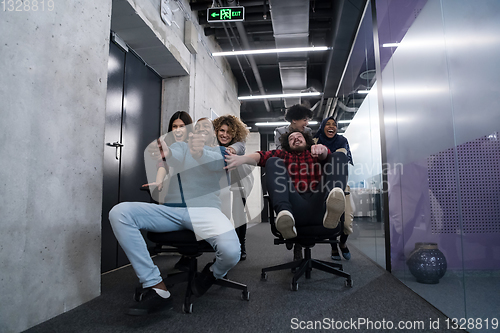 Image of multiethnics business team racing on office chairs