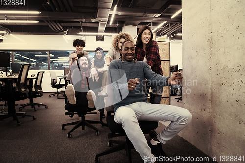 Image of multiethnics business team racing on office chairs