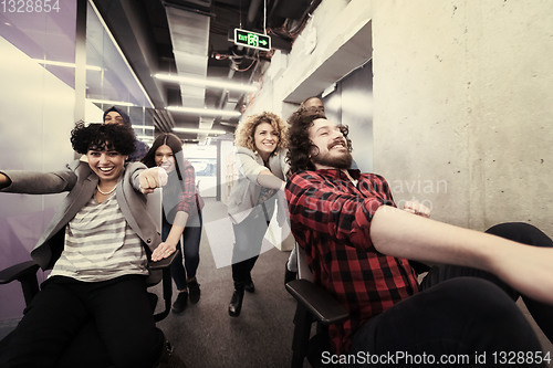 Image of multiethnics business team racing on office chairs