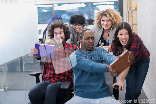 Image of multiethnics business team racing on office chairs