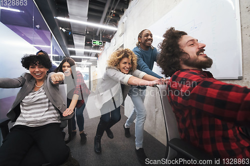 Image of multiethnics business team racing on office chairs