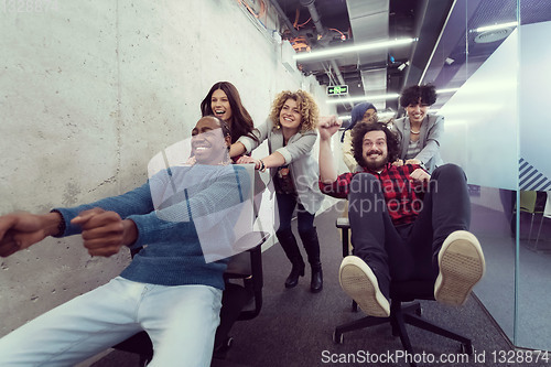 Image of multiethnics business team racing on office chairs