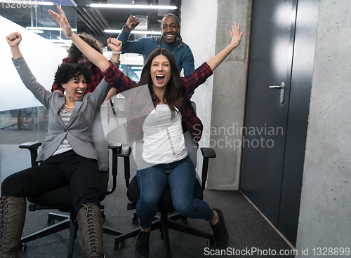 Image of multiethnics business team racing on office chairs