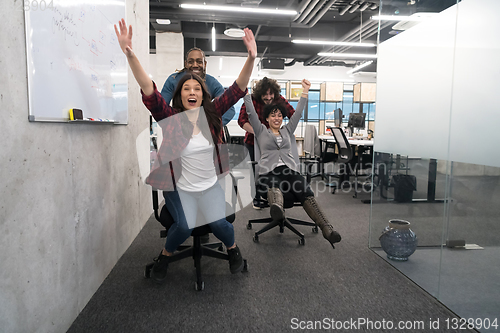 Image of multiethnics business team racing on office chairs