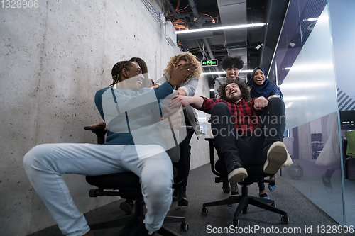 Image of multiethnics business team racing on office chairs