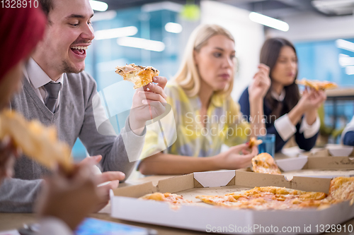 Image of multiethnic business team eating pizza