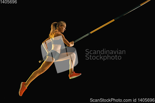 Image of Female pole vaulter training on black studio background in neon light