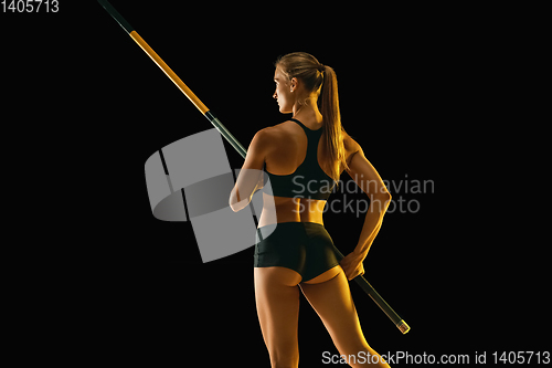 Image of Female pole vaulter training on black studio background in neon light