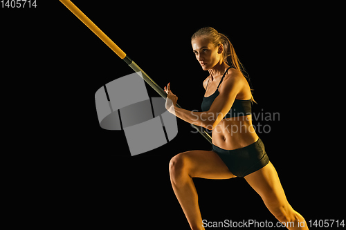 Image of Female pole vaulter training on black studio background in neon light