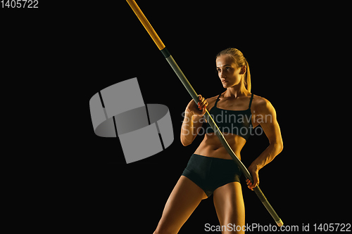 Image of Female pole vaulter training on black studio background in neon light