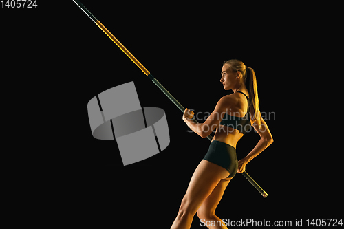 Image of Female pole vaulter training on black studio background in neon light