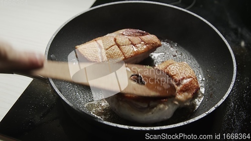 Image of Roast duck breast in frying pen closeup footage