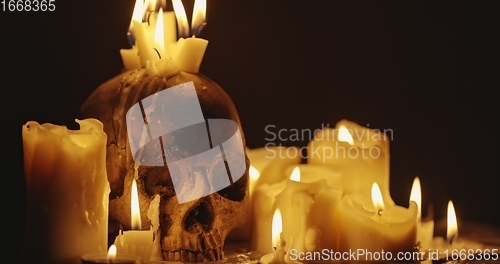 Image of Candles and human skull in darkness closeup footage