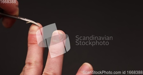 Image of Man cuts fingernail for himself
