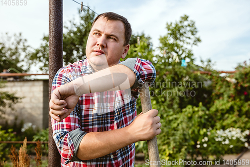 Image of Young farmer working at his garden in sunny day