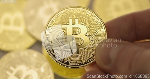 Image of Inspecting Physical bitcoin held in hands closeup