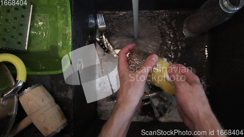 Image of Washing dirty dishware in black sink