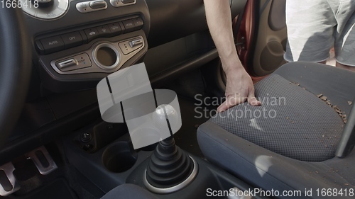 Image of Man cleaning dirty car interior with vacuum cleaner