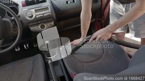 Image of Man cleaning dirty car interior with vacuum cleaner