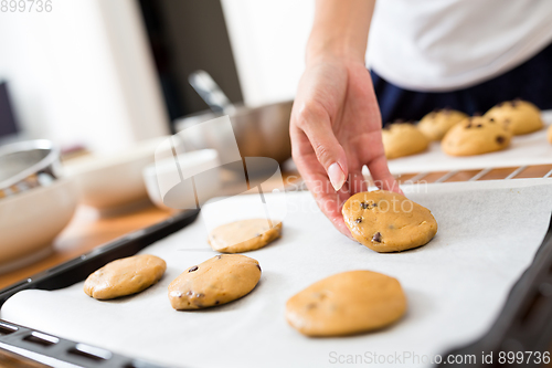 Image of Woman putting paste on metal tray and prepare to cook