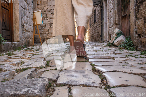 Image of Detail shot of female legs wearing comfortable travel sandals walking on old medieval cobblestones street dring sightseeing city tour. Travel, tourism and adventure concept