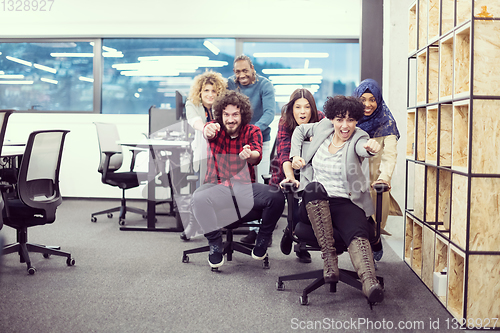 Image of multiethnics business team racing on office chairs